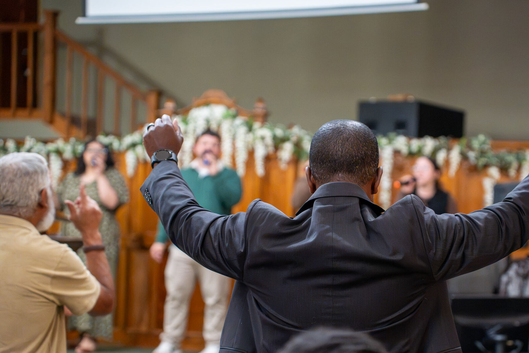 A man worshiping with his arms open wide during a CLA gathering